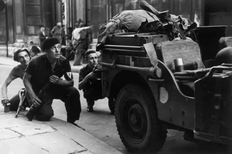 Robert Capa – Membres de la résistance accroupis derrière un camion pendant la Libération, Paris, France, 25 août 1944