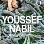 Exhibition poster showing a nude man reclining on large tree roots, with bold white text 'Youssef Nabil' and 'De Rêver Encore'; Musée d’Orsay dates shown at bottom.