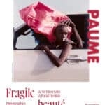 Poster for the 'Fragile beauté' photography exhibition, showing a girl leaning from a white car window with a pink cloth on her head.