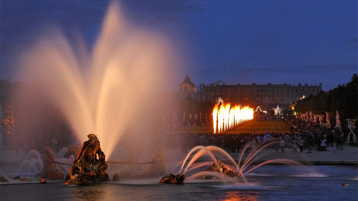 Gerbes pyrotechniques croisées au-dessus d’un bassin lors des Grandes Eaux Nocturnes