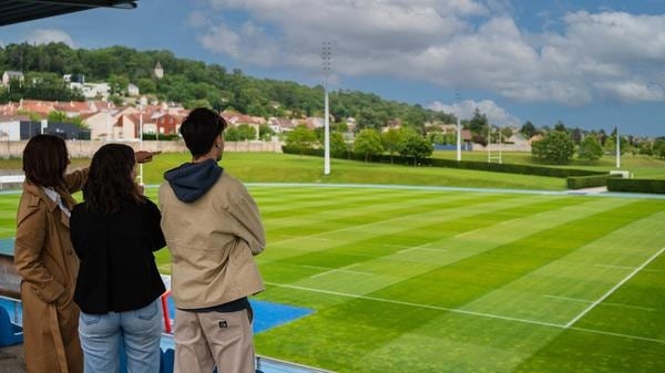 Visiteurs observant le terrain d’honneur depuis la tribune du Centre National de Rugby